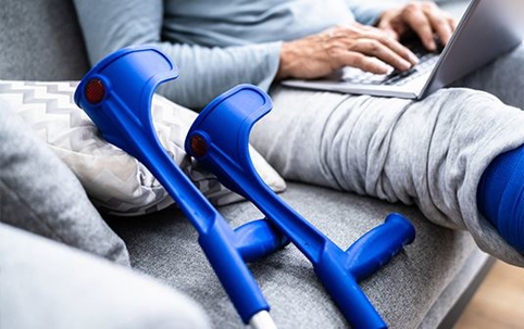 Person with crutches using computer